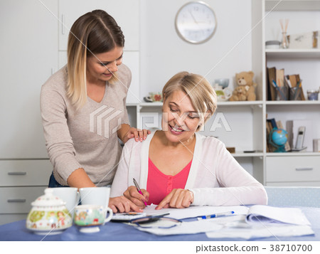 Daughter helps mother to lead home accounting Daughter helps mother to lead home accounting 38710700