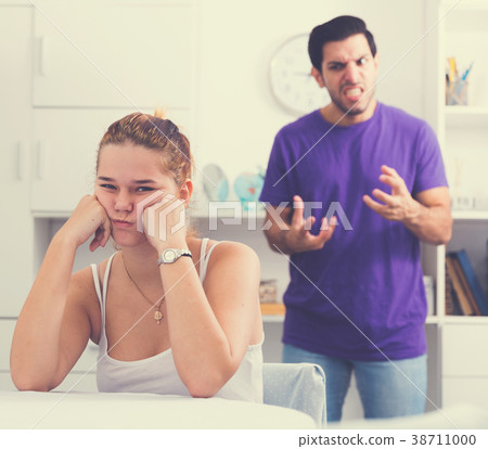Stressed woman at table with screaming husband behind 38711000