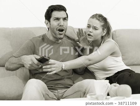 Couple on sofa quarreling because of TV remote 38711109