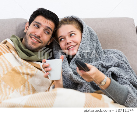 Happy couple nestling on couch watching TV 38711174