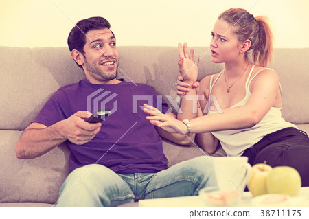 Woman trying to take away TV remote from boyfriend 38711175