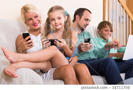 Portrait of family playing with gadgets at home 38711708