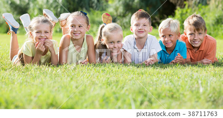 Group of glad kids lying on green grass in park Group of glad kids lying on green grass in park 38711763