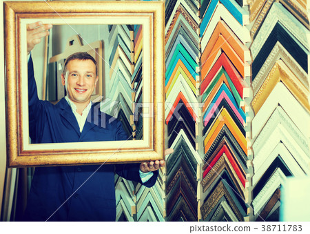 portrait of man seller working with picture frames in atelier 38711783