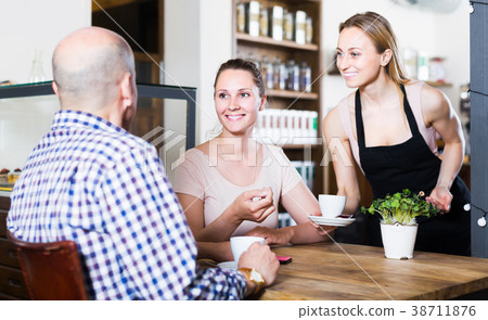 Middle aged man and young woman talking in cozy cafe Middle aged man and young woman talking in cozy cafe 38711876