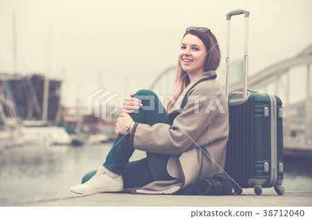 woman with luggage posing at quay and smiling 38712040