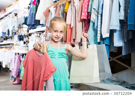 portrait of girl standing in kids clothes store with shopping bags 38712204