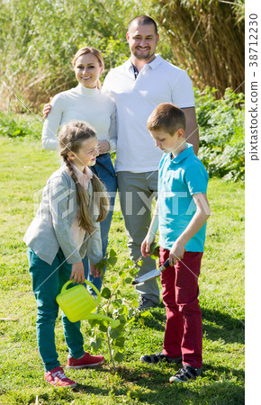 Parents with two kids planting a bush . Parents with two kids planting a bush . 38712230