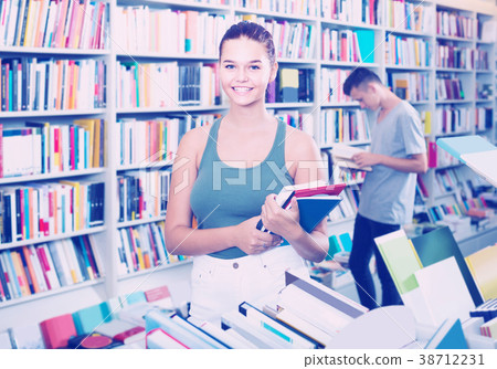 teenage girl holding new books pile in shop teenage girl holding new books pile in shop 38712231