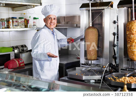 Cheerful mature man cook cutting kebab meat on kitchen Cheerful mature man cook cutting kebab meat on kitchen 38712358