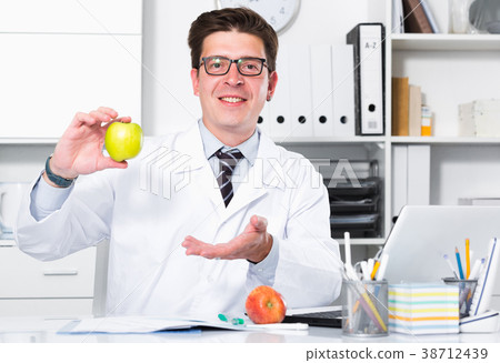 Doctor dentist in uniform demonstrating benefit of apples Doctor dentist in uniform demonstrating benefit of apples 38712439