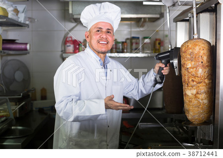 mature chef slicing kebab in fast food. 38712441