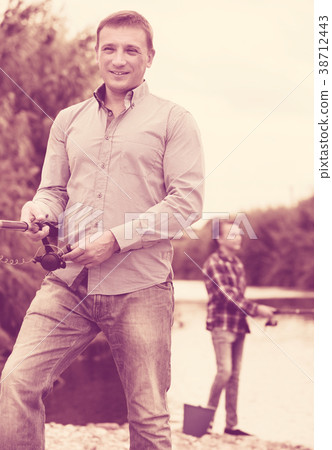 Man fishing using rod on lake 38712443