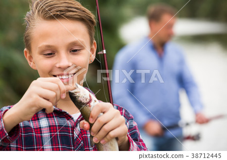 teenager boy holding catch fish on hook . teenager boy holding catch fish on hook . 38712445