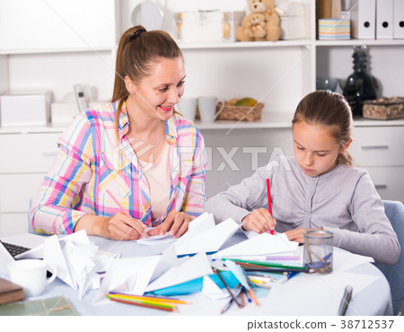 Mother and smiling daughter learning to do paper figurines Mother and smiling daughter learning to do paper figurines 38712537
