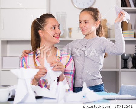 Mother and smiling daughter learning to do paper figurines Mother and smiling daughter learning to do paper figurines 38712541