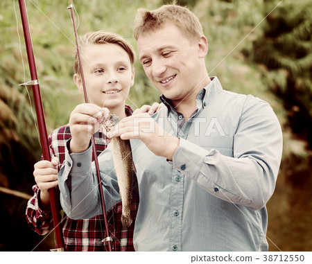 Laughing man with son looking at fish on hook Laughing man with son looking at fish on hook 38712550