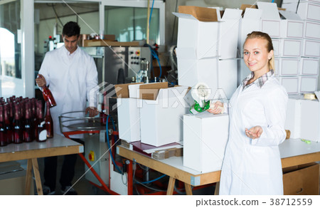 Happy woman in uniform packing wine bottles 38712559