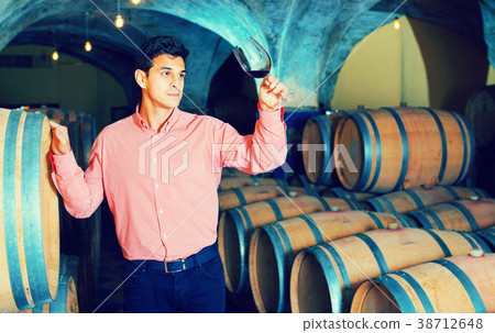 Male customer tasting red wine from wooden barrels Male customer tasting red wine from wooden barrels 38712648
