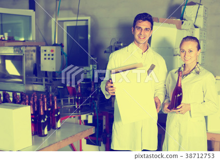 Two happy employees standing in packaging section on wine manufactory Two happy employees standing in packaging section on wine manufactory 38712753