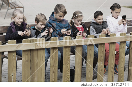 Little boys and girls sitting with smartphones Little boys and girls sitting with smartphones 38712754