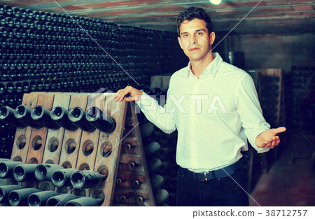 Male wine maker showing bottles on winery Male wine maker showing bottles on winery 38712757