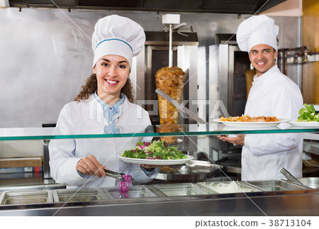 Portrait of two hospitable chefs with kebab at fastfood place Portrait of two hospitable chefs with kebab at fastfood place 38713104