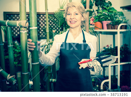 Positive female florist standing amongst plants 38713191