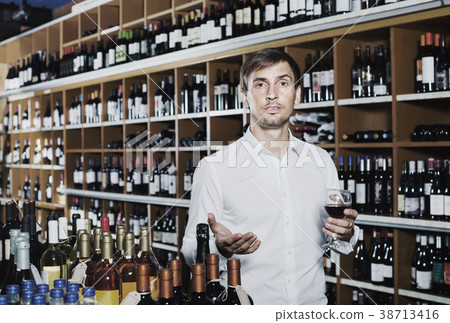 Smiling man trying glass of alcohol beverage Smiling man trying glass of alcohol beverage 38713416
