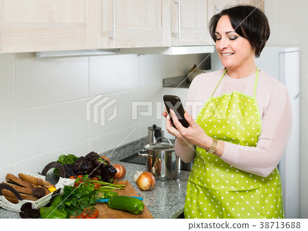 housewife in apron taking photo of dinner indoors housewife in apron taking photo of dinner indoors 38713688