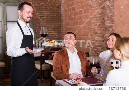 positive waiter placing order in front of guests 38713768