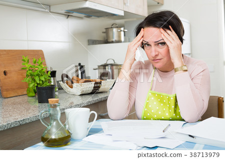 Upset woman with bills crying at home 38713979
