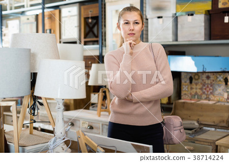 woman buyer standing in furniture shop choosing modern torchere woman buyer standing in furniture shop choosing modern torchere 38714224