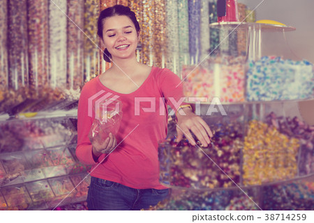 Happy girl in store is picking up candies Happy girl in store is picking up candies 38714259
