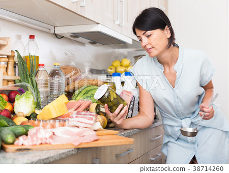 Portrait of female who is standing with conservation tomato on kitchen Portrait of female who is standing with conservation tomato on kitchen 38714260