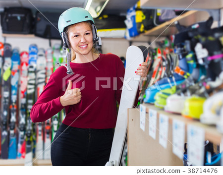 Woman in helmet is demonstraiting ski in shop. 38714476