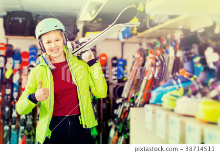 woman in jacket and helmet is demonstraiting ski in shop. 38714511