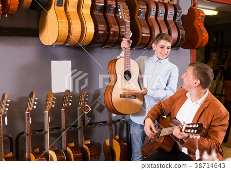 Boy and father choosing acoustic guitar Boy and father choosing acoustic guitar 38714643