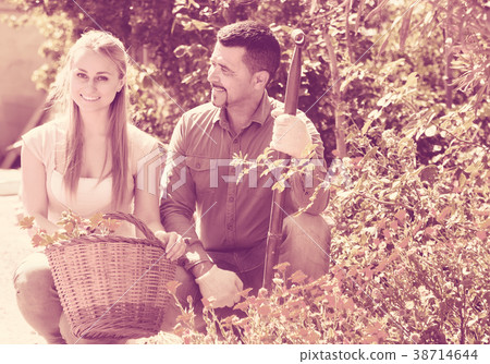 Woman and man holding basket with flowers. Woman and man holding basket with flowers. 38714644
