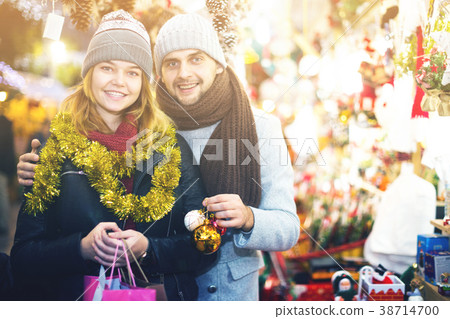Positive young couple buying decoration at Christmas Fair 38714700