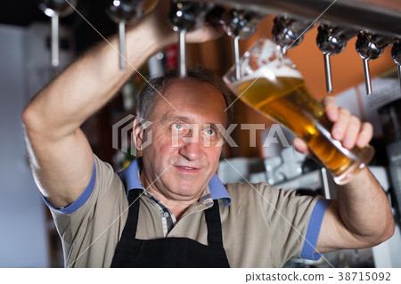 Smiling barman is pouring unbottled beer for next client 38715092