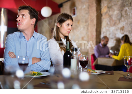 Young emotional couple quarreled in restaurant sitting at served table 38715116
