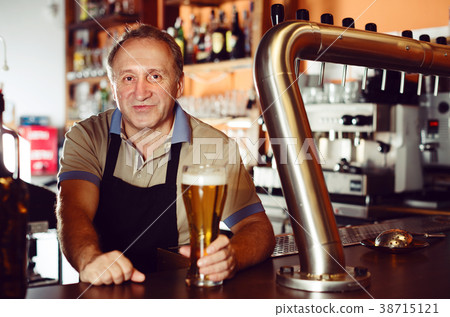 Adult barman is giving beer with foam to client 38715121