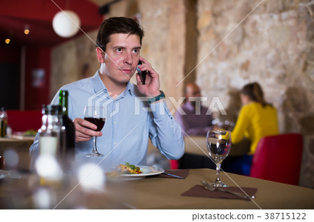 Young man talking on phone during evening meal 38715122