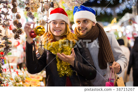 Girl with boy in Christmas hat choosing decorations Girl with boy in Christmas hat choosing decorations 38715207