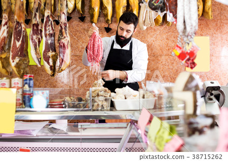 Male seller offering delicious sausages 38715262
