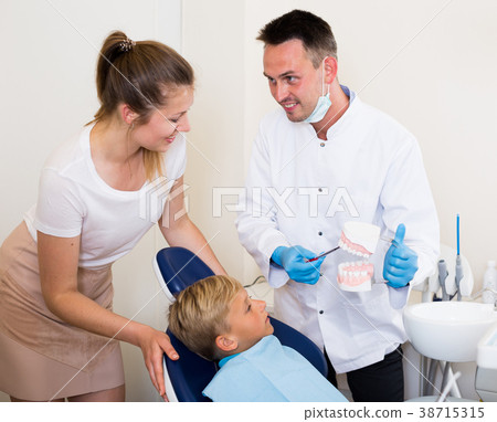 Adult doctor in uniform is telling to young boy and mother about hygiene Adult doctor in uniform is telling to young boy and mother about hygiene 38715315