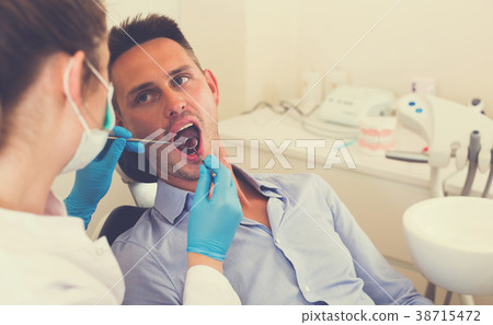 Professional in uniform is taking examination of an adult man on the chair 38715472