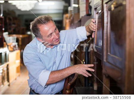 Mature male is choosing old buffet for home 38715508