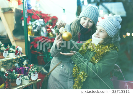 Young girl and her mother are choosing decorations for Christmas tree Young girl and her mother are choosing decorations for Christmas tree 38715511